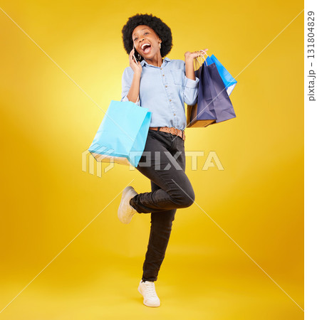 Shopping bag, excited phone call and portrait black woman with sales product, discount fashion deal or mall store present. Talking, designer gift and happy customer chat isolated on yellow background 131804829