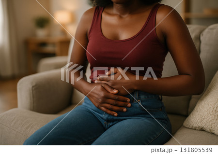 Young woman sitting on sofa holding stomach with discomfort, experiencing abdominal pain in casual home setting, AI Generative Young woman sitting on sofa holding stomach with discomfort, experiencing abdominal pain in casual home setting, AI Generative 131805539