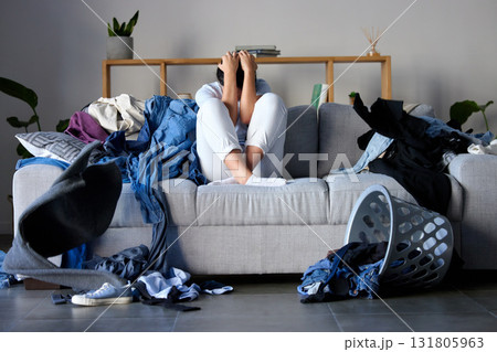 Laundry, clothes and woman on sofa frustrated, angry and upset from cleaning, housework and washing basket. Housekeeping service, burnout and sad girl in living room with chaos, material and clothing 131805963