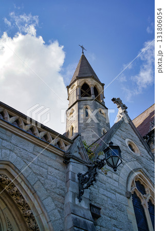 An architectural detail of a historic building in Dublin, Ireland, showcasing its stone facade and a bell tower under a bright blue sky. 131806054