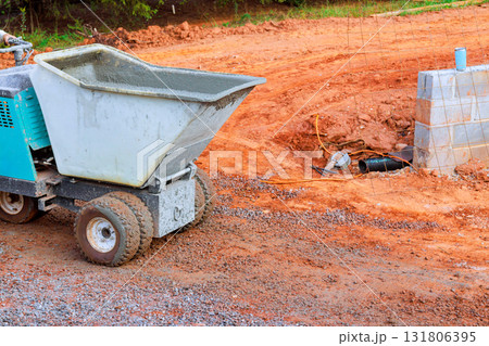 Small concrete mixer is on construction site, using concrete wheelbarrow buggy truck 131806395