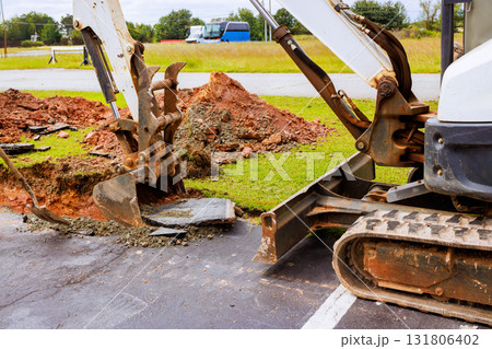 Excavator removes asphalt, soil at construction site while vehicles are. Excavator removes asphalt, soil at construction site while vehicles are. 131806402