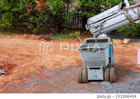 Concrete mixer pours new cement into dumper wheelbarrow buggy truck on construction site 131806404
