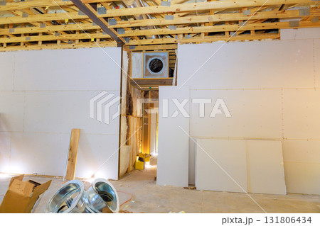 Workers are installing drywall in large room, with exposed framing, tools scattered around construction site. Workers are installing drywall in large room, with exposed framing, tools scattered around construction site. 131806434