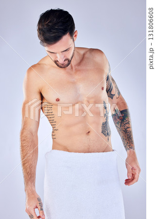 Body, health and man in towel in studio after shower, cleaning or bathing for hygiene and wellness isolated on a gray background. Topless, body art and male fitness model with tattoos, abs and muscle Body, health and man in towel in studio after shower, cleaning or bathing for hygiene and wellness isolated on a gray background. Topless, body art and male fitness model with tattoos, abs and muscle 131806608