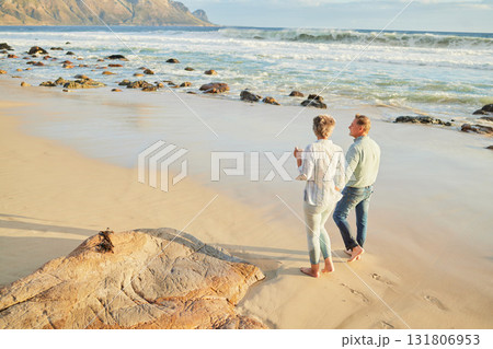 Beach, love and a senior couple walking on the sand by the ocean or sea for romance or dating at sunset. Nature, summer or back with a mature woman and man taking romantic walk together on the coast 131806953