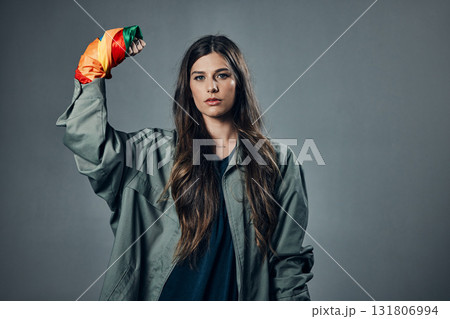 Woman, protest and rainbow fist for gay, LGBTQ or human rights against gray studio background. Portrait of female activist standing ready in fighting for equality, empowerment or sexuality on mockup 131806994