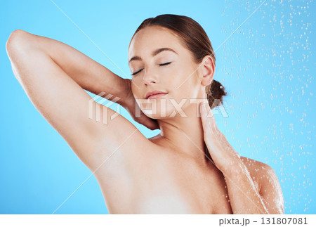 Beauty, shower and woman in a studio with a wellness, health and self care body routine. Skincare, water and female model washing while doing a luxury skin treatment isolated by a blue background. 131807081