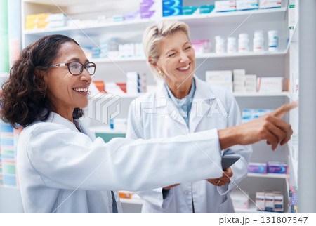 Pharmacy women, shelf and pointing together with smile, stock and product for medical wellness in store. Pharmacist training, management and teamwork for medicine, service and healthcare in shop 131807547
