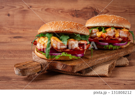 two shrimp burgers and buns with sesame seeds, bacon, lettuce, tomatoes and onions,on a wooden board, rustic style, two shrimp burgers and buns with sesame seeds, bacon, lettuce, tomatoes and onions,on a wooden board, rustic style, 131808212