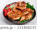 Baked quail, served on a plate with crispy lettuce leaves, fresh tomatoes and herbs, on a dark plate, homemade, 131808235