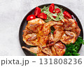 Baked quail, served on a plate with crispy lettuce leaves, fresh tomatoes and herbs, on a dark plate, homemade, 131808236