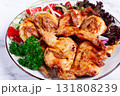 Baked quail, served on a plate with crispy lettuce leaves, fresh tomatoes and herbs, on a white plate, homemade, 131808239