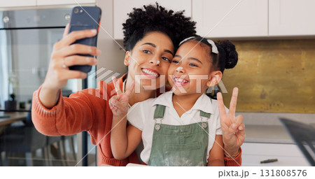 Mom, girl and selfie in kitchen, peace sign and smile with funny face, memory and post on web. Photography, mother and daughter with baking, learning or happy with food, social media or flour on nose 131808576