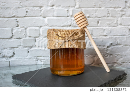 Honey glass jar with honeycomb and wood spoon stay on the stone table. Honey glass jar with honeycomb and wood spoon stay on the stone table. 131808871