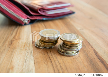 Coins stack on the wood table near the black leather partmone. Wallet with european money for commerce business concept. Coins stack on the wood table near the black leather partmone. Wallet with european money for commerce business concept. 131808872