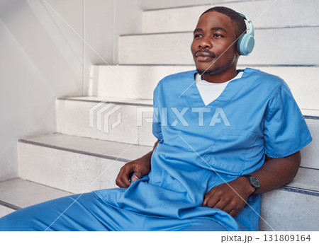 Break, music and African doctor with headphones for a podcast, radio and audio on hospital stairs. Freedom, thinking and a male nurse listening to a track or songs while working in healthcare 131809164