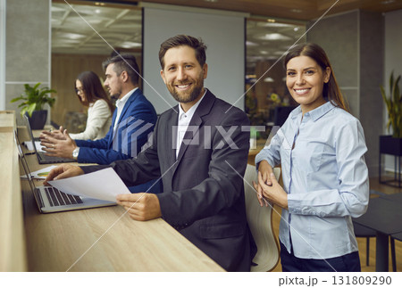 Portrait of happy, smiling business man and woman colleagues at work in the office 131809290