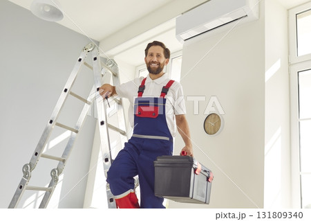 Portrait of electrician with screwdriver looking at camera and smiling maintaining air conditioner 131809340
