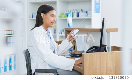 Young pharmacist working on computer at a pharmacy counter. Woman using technology to access drug database, does inventory checkup and dispensing online medicine prescriptions in a drugstore. Young pharmacist working on computer at a pharmacy counter. Woman using technology to access drug database, does inventory checkup and dispensing online medicine prescriptions in a drugstore. 131810050