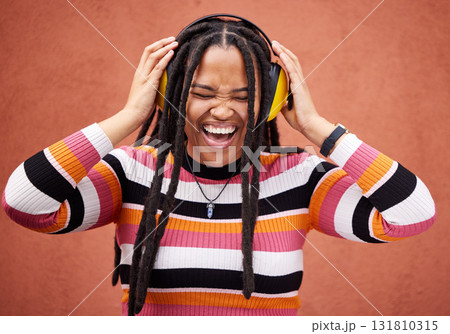 Black woman, music headphones and happiness by wall in city for walk, adventure and comedy album. Young gen z girl, audio streaming and listen to comic podcast on website, radio and happy in metro 131810315