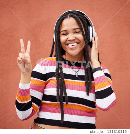 Portrait, headphones and black woman with peace sign isolated on orange wall for gen z music or mental health. Young person or v hands of youth listening to audio 5g technology or streaming services 131810316