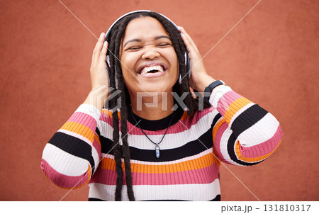 Black woman, music headphones and happy by wall in city for walk, adventure and me time with smile. Young gen z girl, audio streaming and excited listening on radio, website and happiness in metro Black woman, music headphones and happy by wall in city for walk, adventure and me time with smile. Young gen z girl, audio streaming and excited listening on radio, website and happiness in metro 131810317