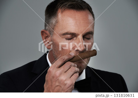 Wealth, vintage and face of man with cigars for smoking habit on gray background for luxury, power and success. Retirement, business gangster and senior male smell tobacco smoke for rich lifestyle 131810631