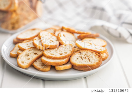 Crispy roasted bruschetta bread on plate on white table. Crispy roasted bruschetta bread on plate on white table. 131810673