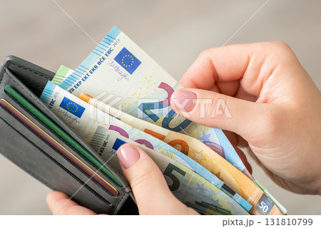Close up of female hands holding grey wallet with 20 and 50 euro banknotes. Purchases, business, finances concept Close up of female hands holding grey wallet with 20 and 50 euro banknotes. Purchases, business, finances concept 131810799