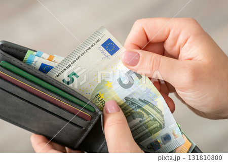 Euro banknote in wallet in hands of a woman, close up. Buying things and paying for them, exchange, small money 131810800