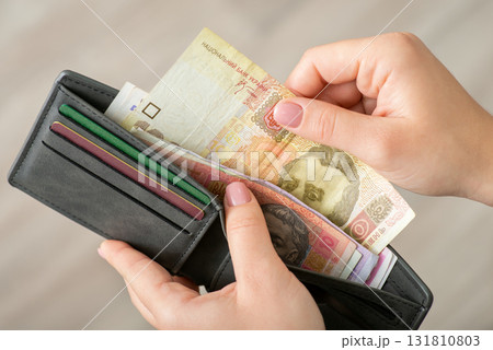 Ukrainian hryvnia various banknotes in female hands in grey wallet. Concept of purchases, buying things, finances 131810803