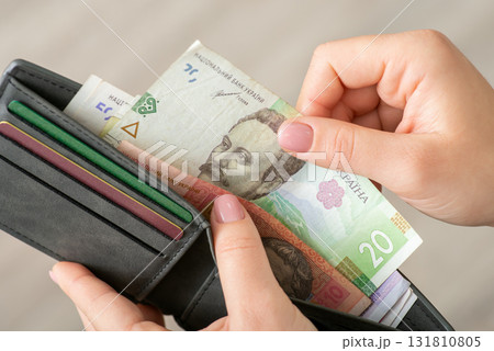 Small money in the wallet, paying for goods concept. Woman dealing with finances, using ukrainian hryvnias while shopping Small money in the wallet, paying for goods concept. Woman dealing with finances, using ukrainian hryvnias while shopping 131810805