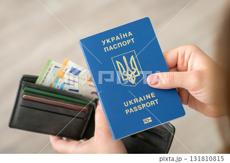 Ukrainian traveling passport in female hands with wallet full of money on the background. Travelling, wealth, richness and finances concept Ukrainian traveling passport in female hands with wallet full of money on the background. Travelling, wealth, richness and finances concept 131810815