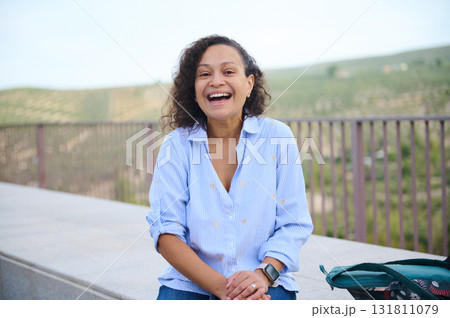 Happy Woman Laughing Outdoors in a Blue Striped Shirt - Casual Portrait on a Sunny Day by the Hills Happy Woman Laughing Outdoors in a Blue Striped Shirt - Casual Portrait on a Sunny Day by the Hills 131811079