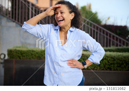 Joyful Woman Laughing Outdoors in Light Blue Striped Shirt, Casual Confidence Joyful Woman Laughing Outdoors in Light Blue Striped Shirt, Casual Confidence 131811082
