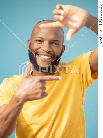 Hands, frame and portrait of black man on blue background for profile picture. Face, happy guy and finger framing for perspective, selfie and vision of happiness, smile and photography sign in studio Hands, frame and portrait of black man on blue background for profile picture. Face, happy guy and finger framing for perspective, selfie and vision of happiness, smile and photography sign in studio 131811221