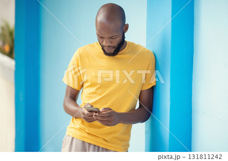 Thinking black man, phone or typing on blue background on social media, internet app or reading news blog. Fashion clothes, person or student on mobile technology with fashion clothes ideas or vision 131811242
