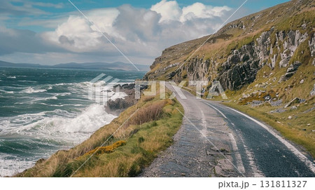 A scenic coastal road curves along a rugged cliff face next to a turbulent ocean A scenic coastal road curves along a rugged cliff face next to a turbulent ocean 131811327