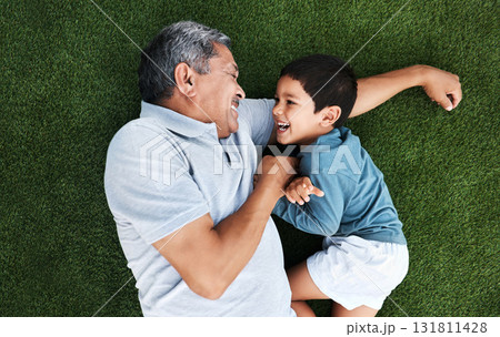 Playful, laughing and grandfather and child in a garden for happiness, playing and cheerful together. Babysit, happy and senior man with a boy kid for quality time during a fun visit on grass 131811428