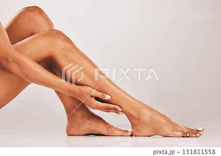Woman, hands and legs in skincare cosmetics, beauty or hair removal against gray studio background. Hand of female touching soft or gentle leg shave for healthy skin, grooming or self love and care Woman, hands and legs in skincare cosmetics, beauty or hair removal against gray studio background. Hand of female touching soft or gentle leg shave for healthy skin, grooming or self love and care 131811558