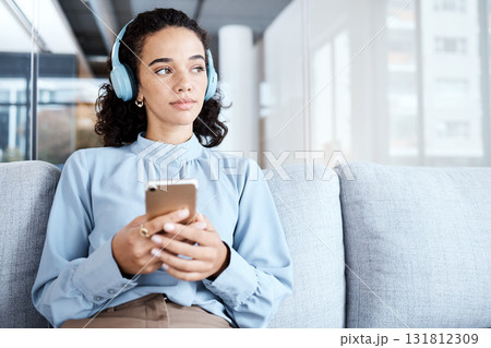 Music headphones, phone and business woman on sofa in office streaming audio. Cellphone, technology and thinking female employee on couch listening to podcast, radio or sound with mobile smartphone. Music headphones, phone and business woman on sofa in office streaming audio. Cellphone, technology and thinking female employee on couch listening to podcast, radio or sound with mobile smartphone. 131812309
