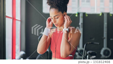 Woman, gym and earphones for music, thinking and listening for inspiration to workout for wellness. African girl, audio streaming subscription and hearing for exercise, training or fitness with sound 131812408