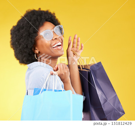 Shopping bag, retail and happy black woman with sales product, discount fashion deal or mall store present. Commerce market, luxury designer gift or chic studio customer isolated on yellow background 131812429