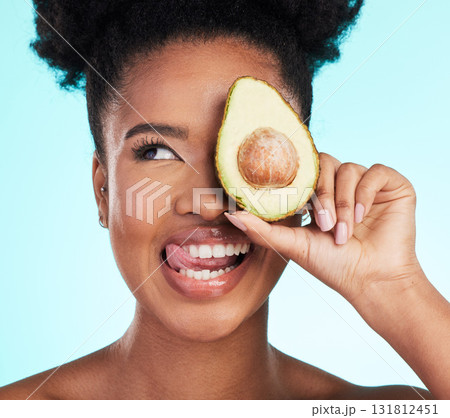 Avocado, woman tongue out and happy face of a young model with skincare, fruit and wellness for diet. Isolated, blue background and studio with a silly person with beauty, cosmetics and healthy food 131812451
