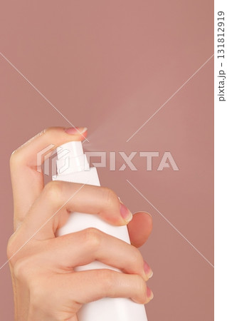 Vertical skincare ad. A woman's hand sprays facial mist, thermal water, or facial toner. The spraying process tones, refreshes, moisturizes, soothes facial skin. Pink backdrop. Copy space Vertical skincare ad. A woman's hand sprays facial mist, thermal water, or facial toner. The spraying process tones, refreshes, moisturizes, soothes facial skin. Pink backdrop. Copy space 131812919
