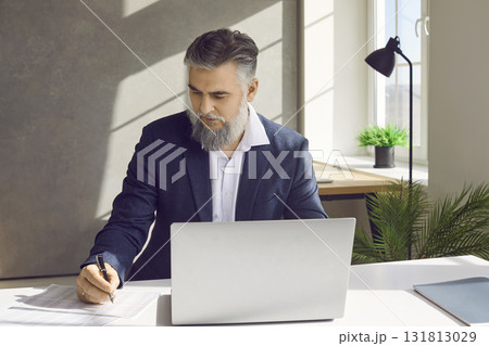 Mature businessman working and taking notes in his office 131813029