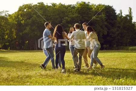 Group of happy friends are having fun and dancing in a circle in the park in summer Group of happy friends are having fun and dancing in a circle in the park in summer 131815327