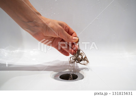 Hand pulls hair out of bathroom drain. Cleaning shower polluted sewerage system. 131815631