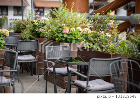 Modern european style empty street cafe with lovely natural flowers near tables in sunny day. Modern european style empty street cafe with lovely natural flowers near tables in sunny day. 131815645